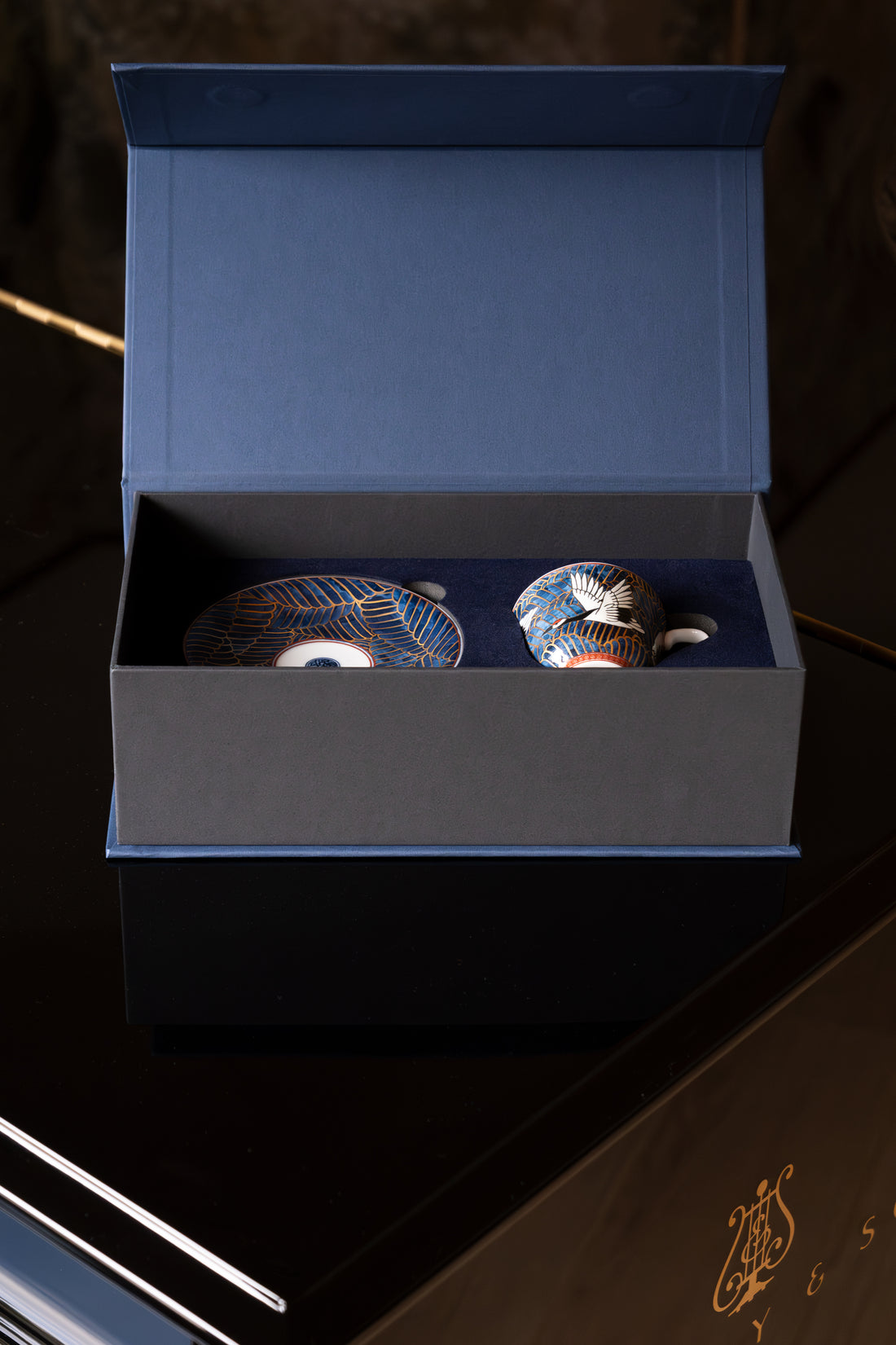 Wooden logs stacked against a wooden building with a grassy area in the foreground.